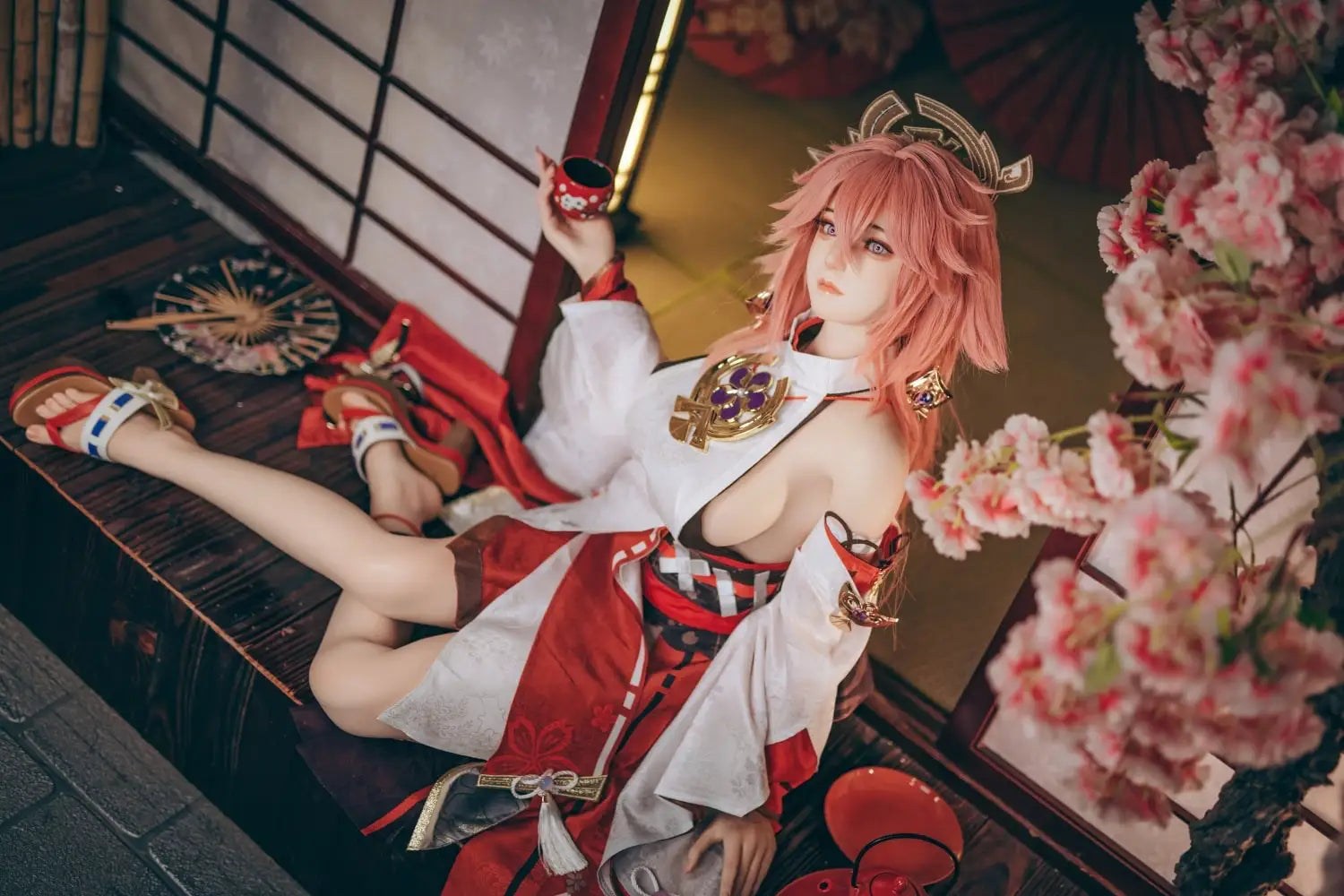  Yae Miko Genshin Impact cosplay sex doll, pink hair, sensual miko outfit, tatami room red cup – anime cosplay lifesize doll by TopLoveDoll,  red bell anklet, wooden geta sandals, Genshin Impact sex doll, sitting on the stairs, legs crossed, holding a J-style red cup, high-angle full shot, horizontal profile