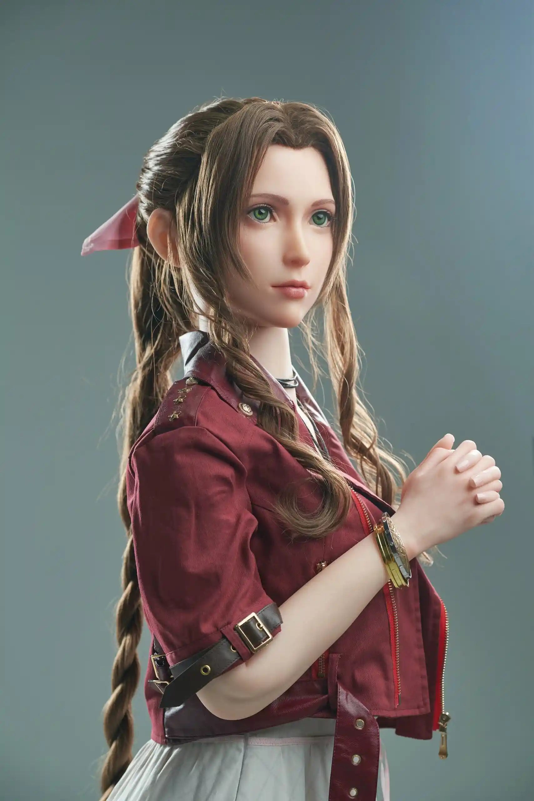 Seyo, brown wavy twin braids, pink hair bow, burgundy leather jacket, white deep-V slip dress, black leather mid-calf boots, green eyes, layered leather string choker, golden layered bracelet, hands holding together like praying, looking away, grey studio background – Tifa Lockhart cosplay sex doll by TopLoveDoll