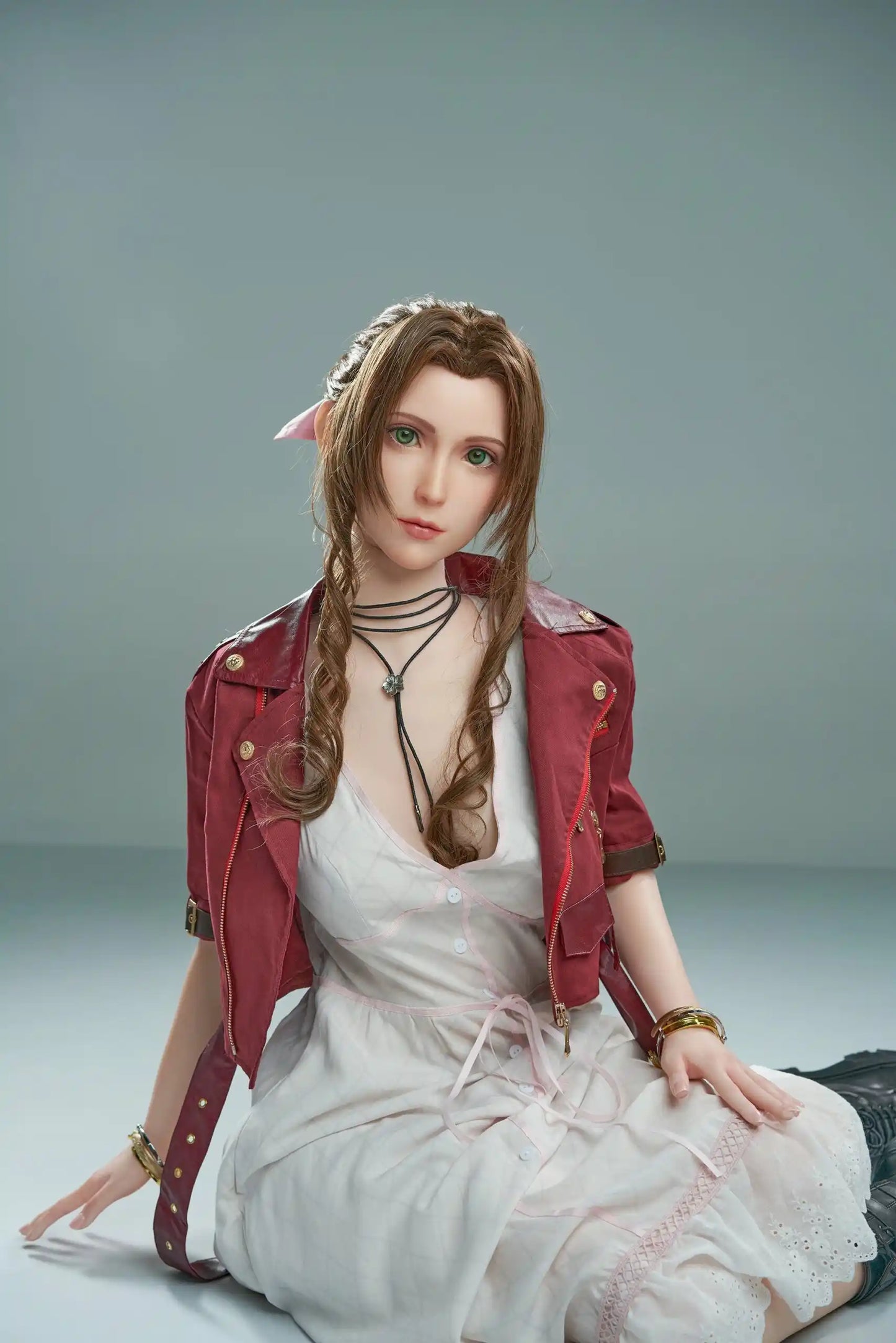 Seyo, brown wavy twin braids, pink hair bow, burgundy leather jacket, white deep-V slip dress, black leather mid-calf boots, green eyes, layered leather string choker, golden layered bracelet, looking at the camera like curious, grey studio background, sitting sideways on the floor – Tifa Lockhart cosplay sex doll by TopLoveDoll