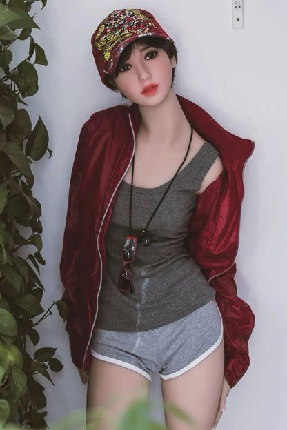Amira short dark brown hair red lip grey tank denim shorts red jacket tomboy feminine contrast pose, standing next to the plants shelf, baseball hat– girl-next-door companion sex doll by TopLoveDoll