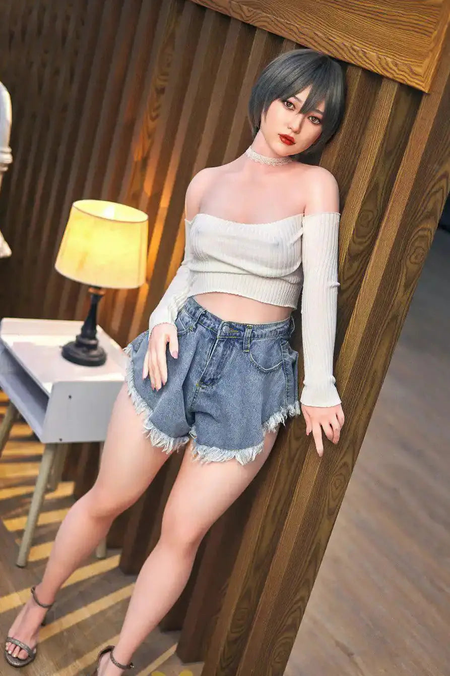 Anya next door sister Asian sex doll - wearing a white off-shoulder top and denim shorts, leaning against a wooden wall, in some yellow-ish lighting scenario, striping herself naked piece by piece, see the full gallery on toplovedoll.com