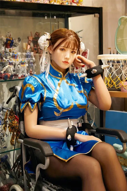 Araya Street Fighter Chun-Li cosplay sex doll, sitting in front of her home figurine exhibits, grey contacts, spiky bracelets- blue qipao, high twin buns - Asian beauty elevated by TopLoveDoll