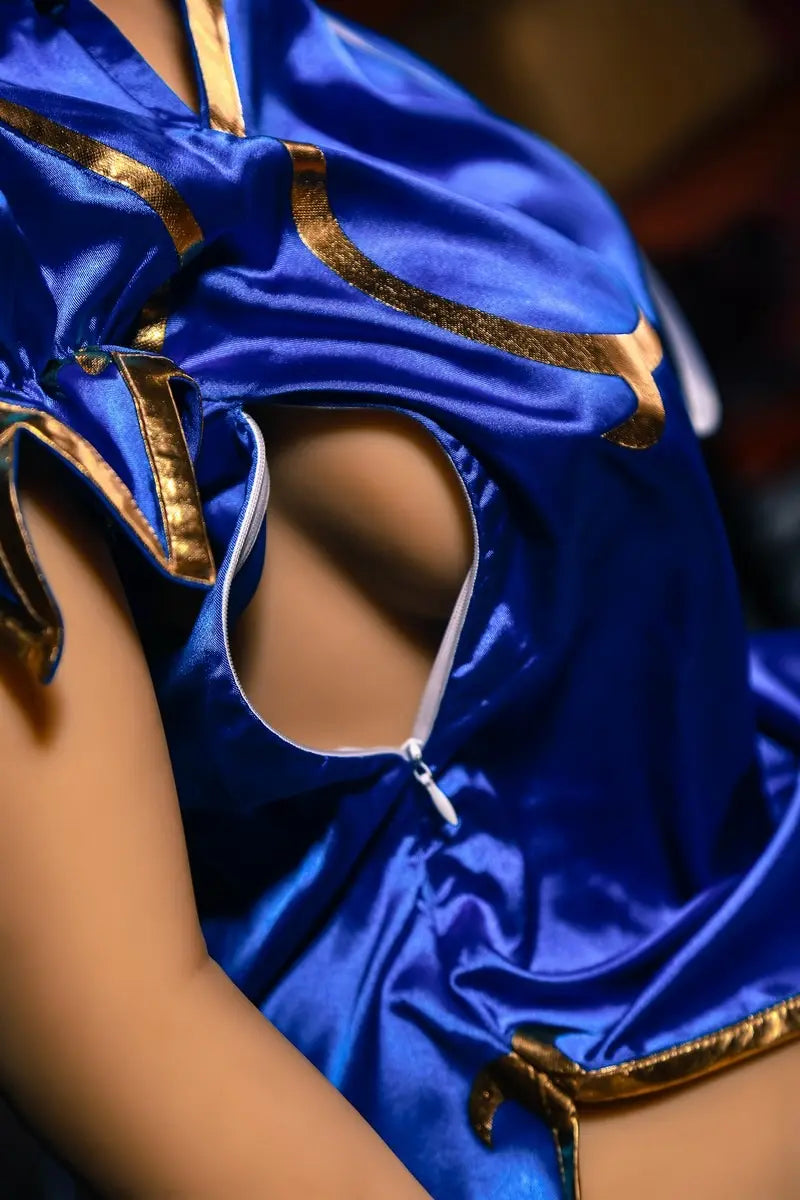 Aubriella Street Fighter Chun-Li cosplay sex doll in blue qipao on a black background, close up of the unzipped zipper crack, showing the side curves of her breasts, looking puzzled- iconic blue qipao fighter fantasy by TopLoveDoll