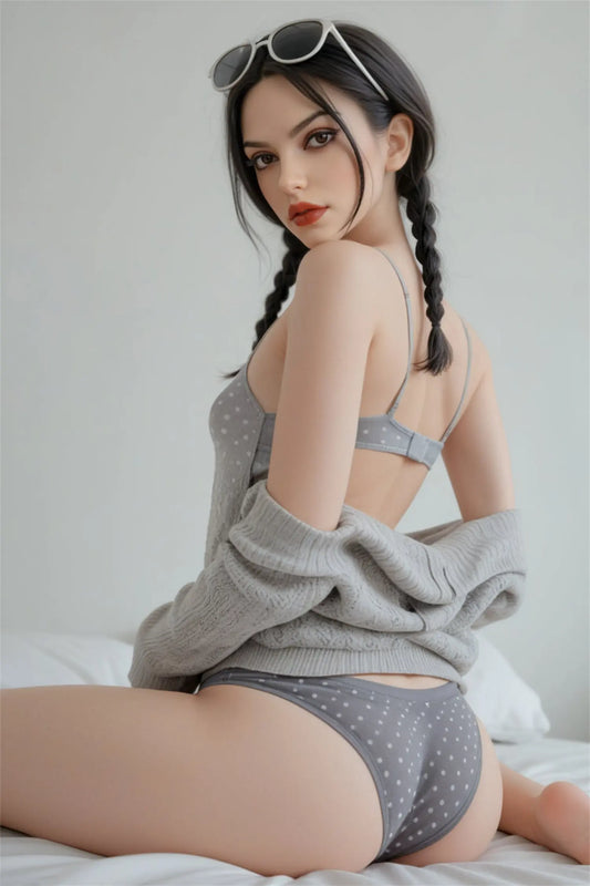 Alexa sex doll over-the-shoulder smoldering gaze, dark brown eyes, long black hair in double braids, red lips, white cat-eye sunglasses on head, grey polka-dot spaghetti-strap crop top, grey polka-dot boyshort underwear, grey oversized knit cardigan slipping off shoulders, kneeling on white bedding with soft white studio background – three-quarter back kneeling shot – lifelike girl-next-door European sex doll by TopLoveDoll